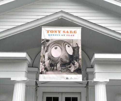 Large exterior banner with pole pockets suspended over door of museum entrance.