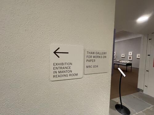 Interior wayfinding directional sign with braille for museum exhibition. Sign reads "exhibition entrance".
