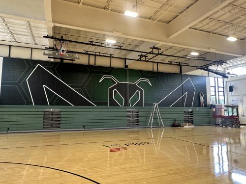 School pride mural, the logo covering the wall behind the bleachers.